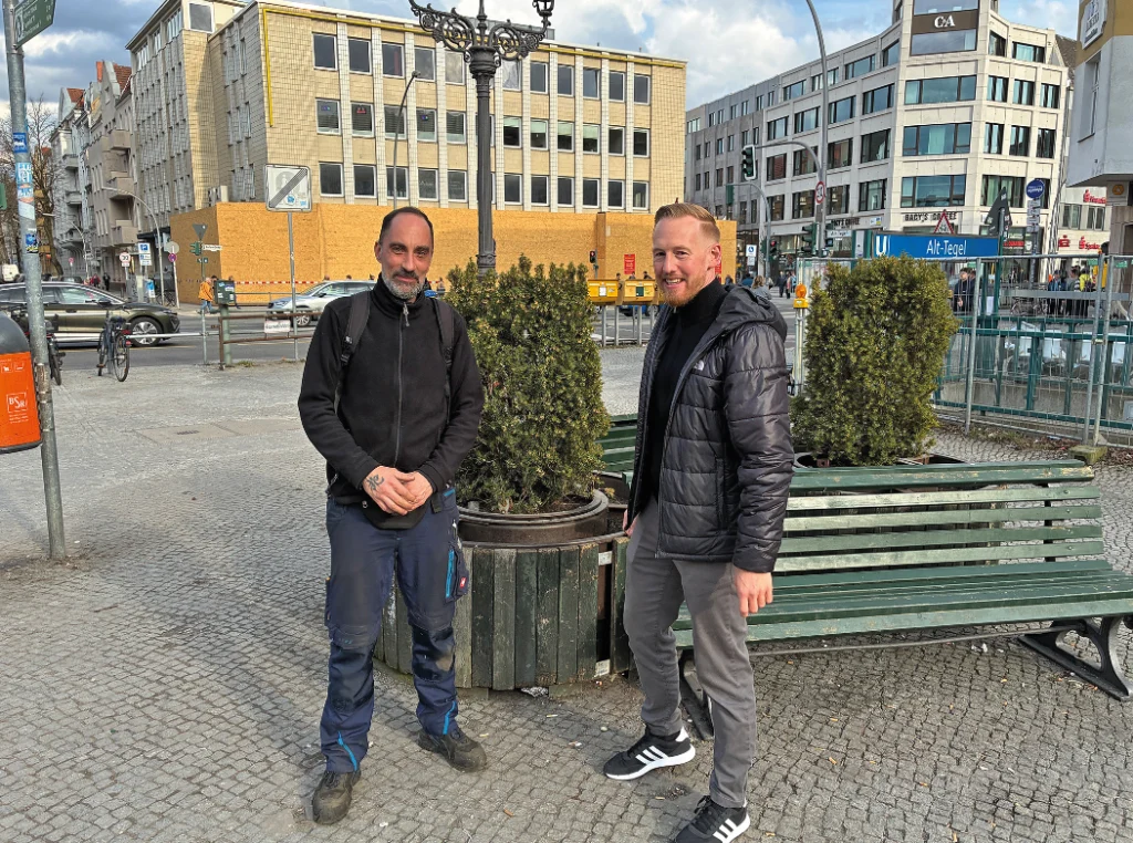 Zwei Männer stehen an einer Bank